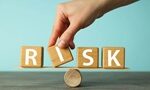 hand putting blocks forming word Risk balancing on a small piece of wood balancing on a round stick