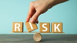 hand putting blocks forming word Risk balancing on a small piece of wood balancing on a round stick