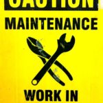 Yellow sign displaying tools and caution maintenance work in progress warning