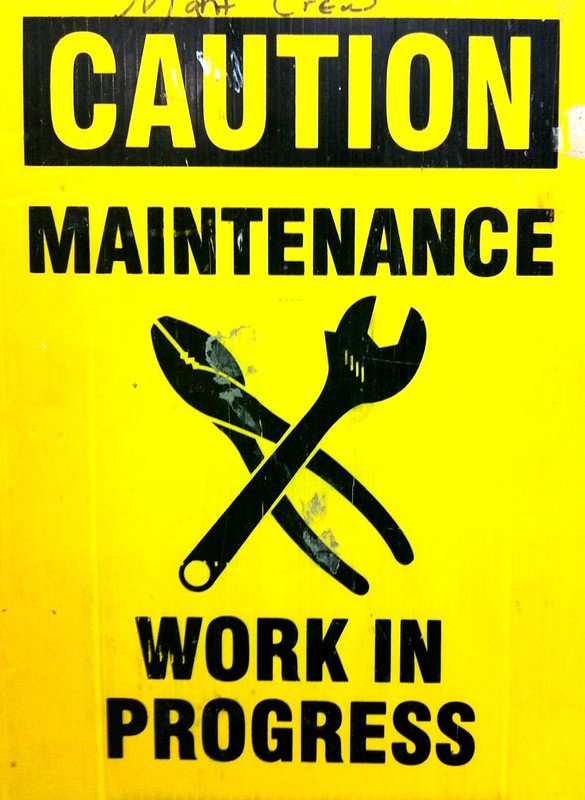 Yellow sign displaying tools and caution maintenance work in progress warning